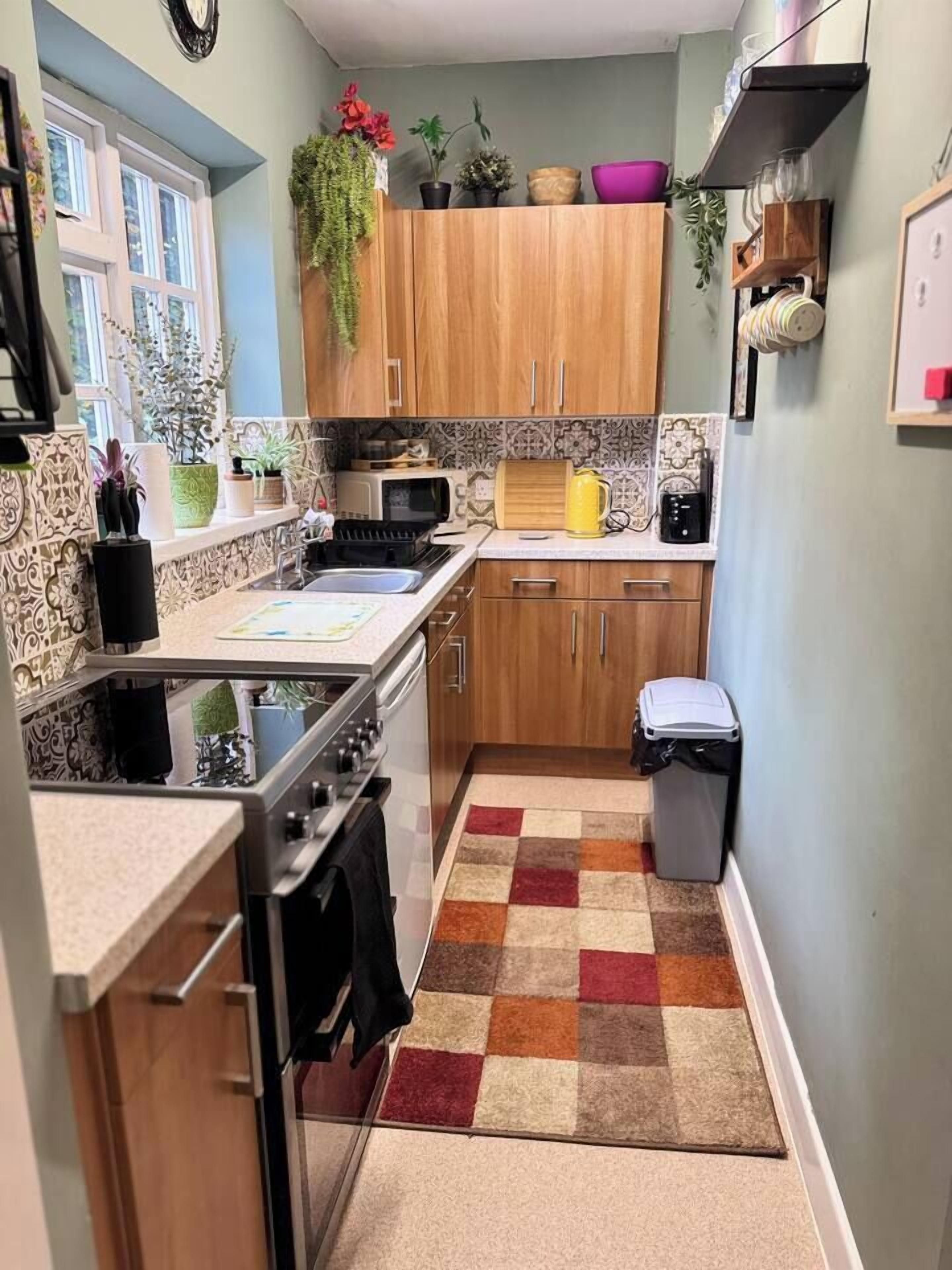 A compact kitchen with a stove, sink, and wooden cabinets.