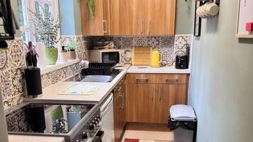 A compact kitchen with a stove, sink, and wooden cabinets.