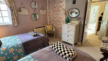 A bedroom with two beds, a dresser, a chair, and a mirror on the wall.
