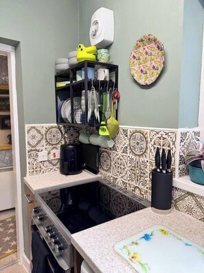 A kitchen with a patterned backsplash, a coffee maker, and a knife block on the counter.