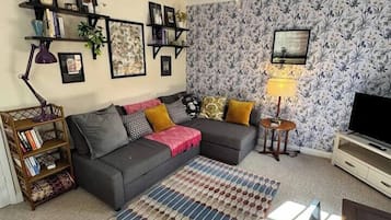 Un salon avec un canapé, une table basse, un téléviseur et un tapis à motifs.