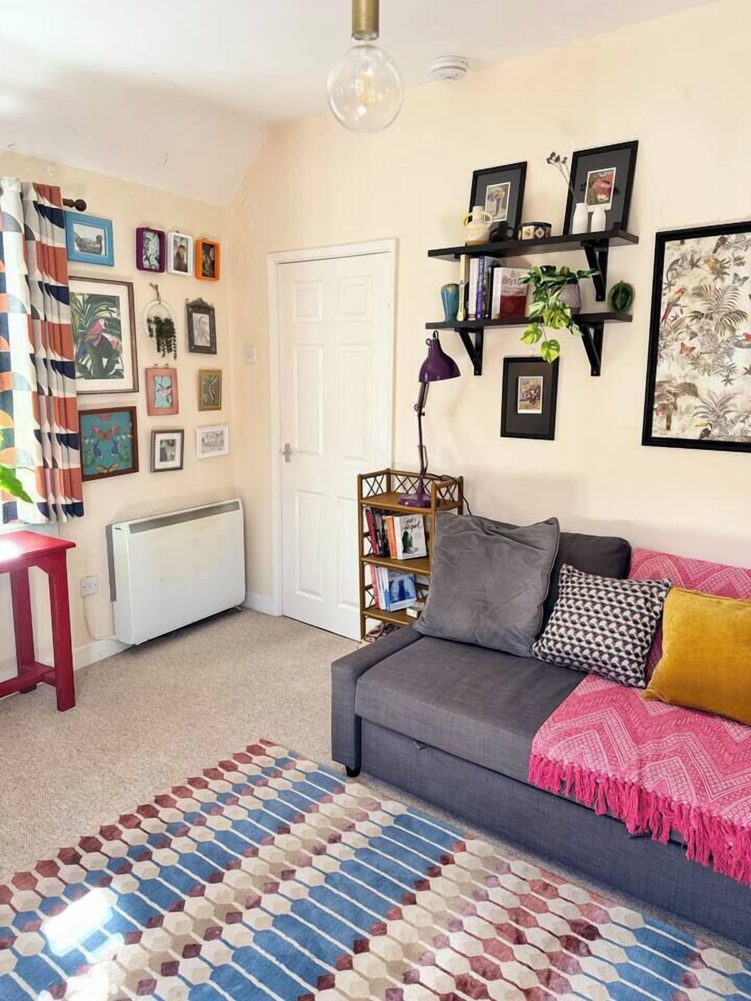 A cozy living room with a sofa, a patterned rug, and a bookshelf.