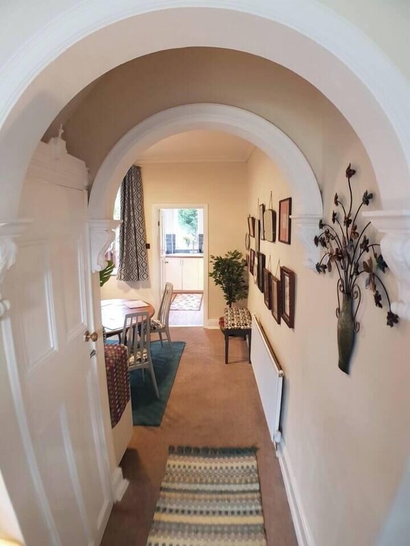 A hallway with an arched doorway leading to a dining area.