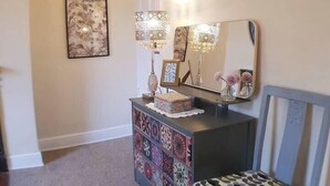 A hallway with a patterned rug, a decorative console table, a mirror, and a chair with a patterned cushion. - #07 Edwardian Terrace in Royal Sutton NEC BHX (Birmingham)