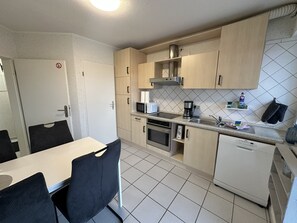 A compact kitchen with a dining area, equipped with a microwave, coffee maker, and a dishwasher. - Cozy vacation rental for workers: Sleeps 4, 2 bedrooms, kitchen, bathroom, balcony (Hopsten)