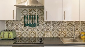 Een keuken met een roestvrijstalen afzuigkap, een vintage groene toaster en een tegelwand met een patroon.