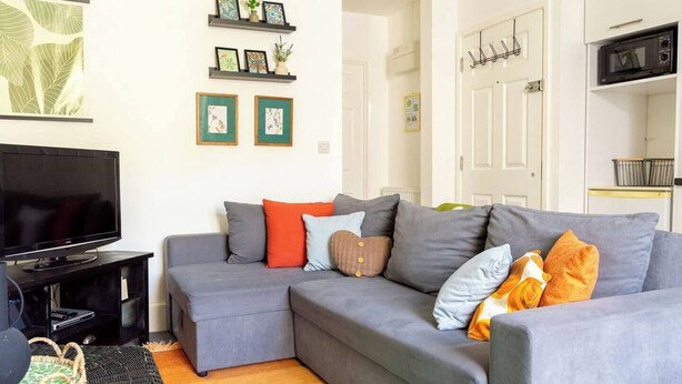 Een woonkamer met een grijze bank, een flatscreen televisie en decoratieve wandkunst.