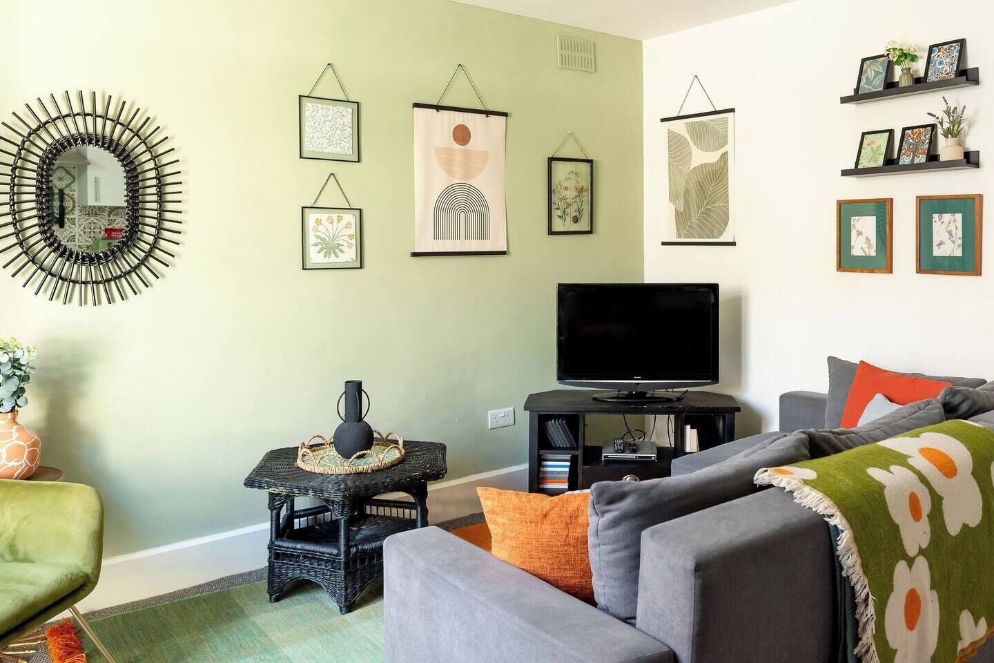 Un salon avec un téléviseur, un canapé et des œuvres d’art décoratives au mur.