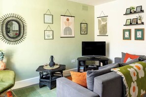 A living room with a television, sofa, and decorative wall art.