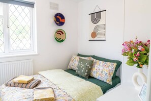 Ein Schlafzimmer mit Bett, Kissen, einem Fenster, einer Heizung und Wanddekorationen.