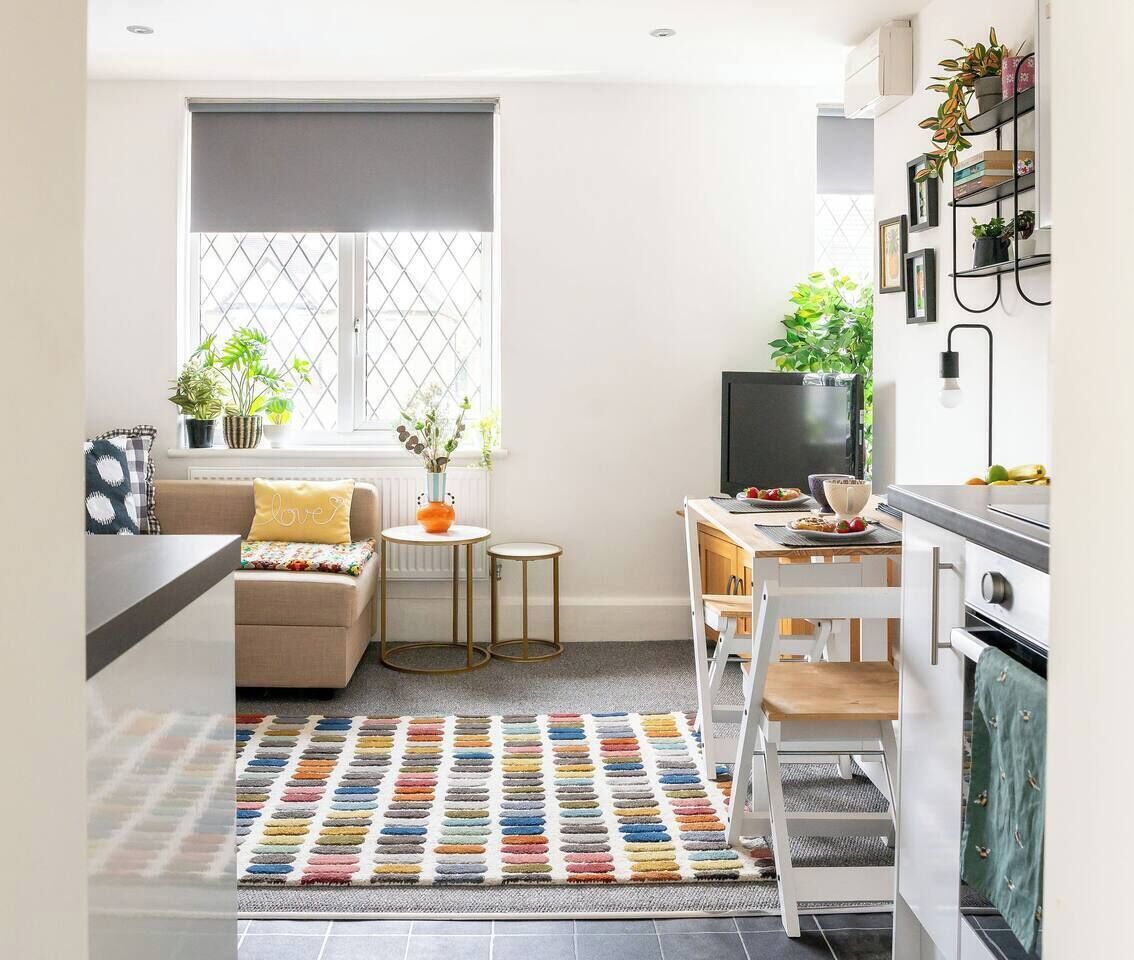 A modern kitchen with a dining area, a sofa, and a TV.