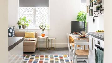 A modern kitchen with a dining area, a sofa, and a TV.