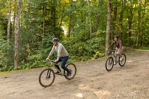 Dos ciclistas en un sendero de tierra rodeado de árboles.