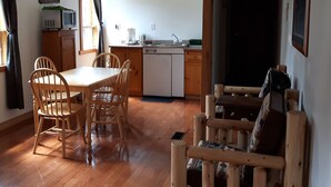 A compact kitchen with a dining area, wooden furniture, and a blackboard.