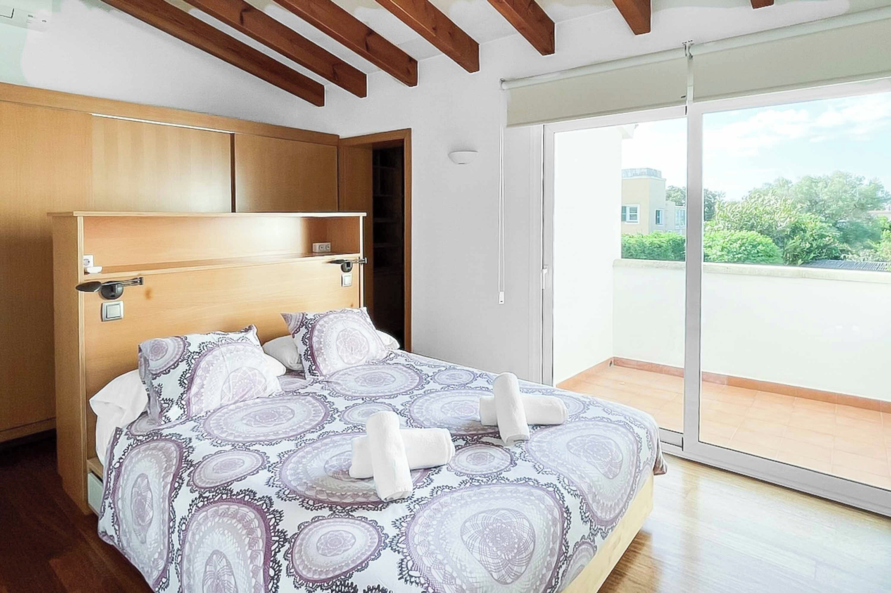 Ein Schlafzimmer mit einem Bett, einem Holzkopfende und einer Schiebetür zu einem Balkon.