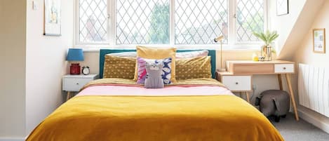 Une chambre à coucher avec un lit, une table de chevet, une lampe et une fenêtre avec des stores.