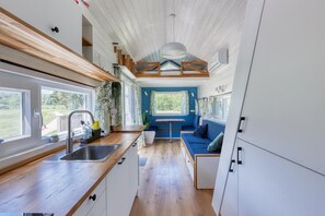 Cuina petita amb rentapelats, taulell de fusta i zona menjador amb sofà blau.