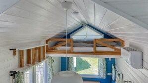 Een slaapkamer in een loft met een schuine plafond, een dakraam en een ingebouwde airconditioning.