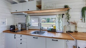 Een keuken met een houten aanrecht, een spoelbak en kastjes. Er is een raam met uitzicht op een buitenruimte.