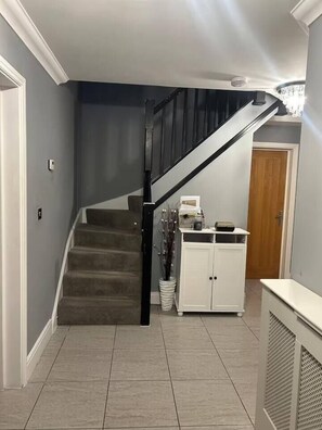 A staircase with a black railing leading to a landing. - #100 Comfortable 4-Bed House in Rugby (Warwickshire)