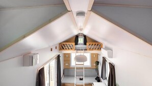 Slaapkamer in een loft met een stapelbed, dakraam en een trap naar een hoger niveau.