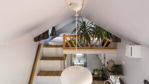 Een slaapkamer in loftstijl met schuine plafonds, een bed, een houten trap, een hanglamp en een potplant.