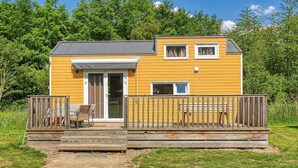 Een klein, gelijkvloers houten huisje met een terras en een schuifdeur.