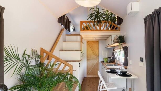 Een compacte keuken met een houten trap, een eethoek en een gezellig zitje.