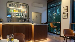 A bar area with a wooden counter, bar stools, and a large window with a view of trees. - Adagio Umbro rooms B&B Tennis Court (Spoleto)