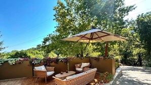 An outdoor patio with wicker furniture, a table, and an umbrella. - Adagio Umbro rooms B&B Tennis Court (Spoleto)