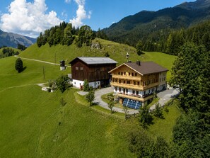 Un edificio a due piani con tetto spiovente, una struttura in legno separata e un pannello solare.