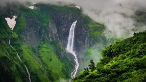 Une cascade entourée de collines verdoyantes.
