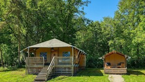 En campingplats med två stugor, varav den ena har en veranda och trappsteg, och den andra har en bänk.