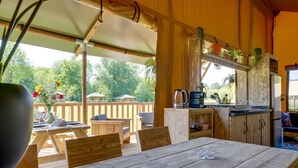 Ein Holztisch mit Stühlen, eine Küchenzeile mit Herd und Spüle sowie ein Blick ins Freie.