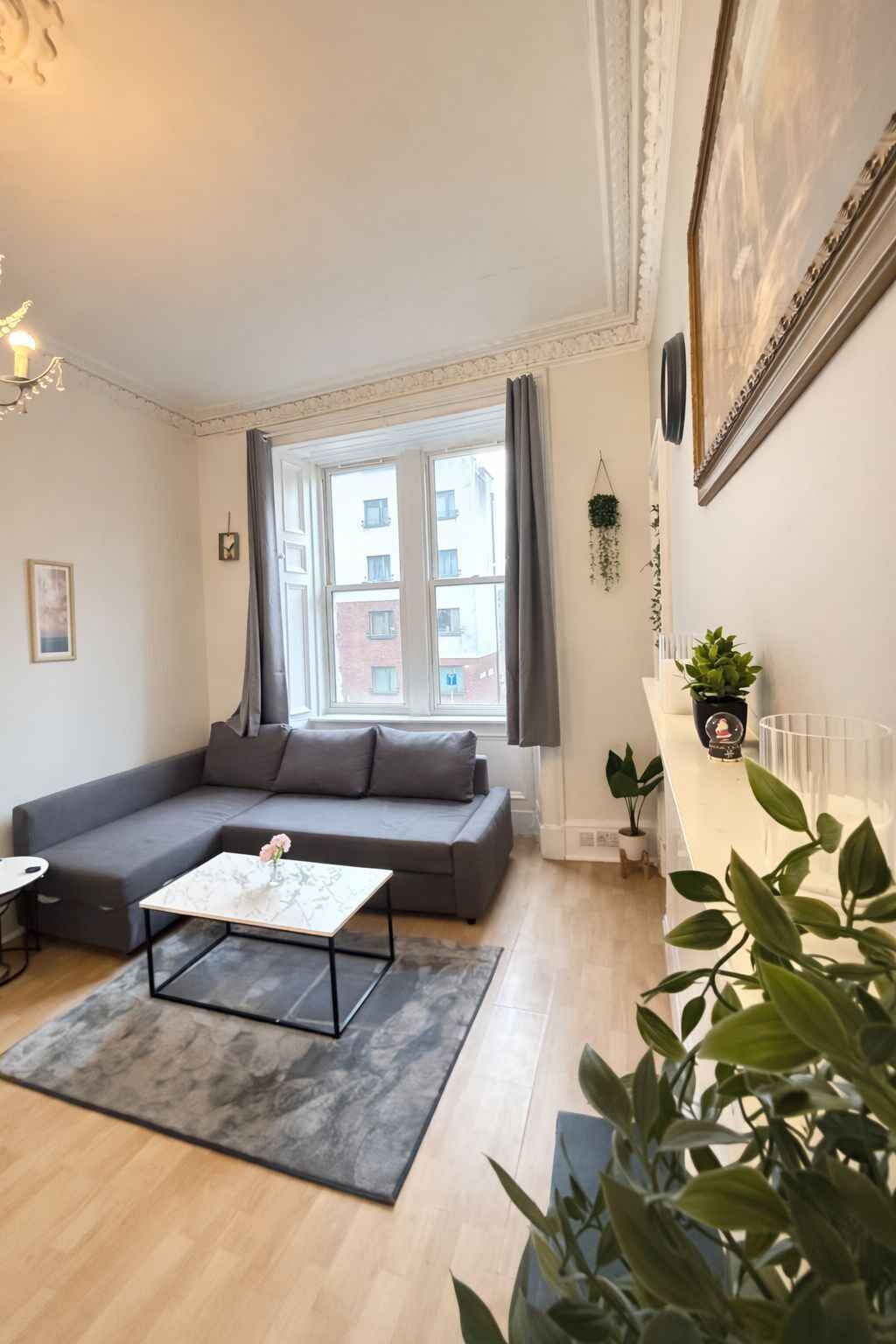 A modern living room with a grey sofa, a coffee table, and a large window with curtains.
