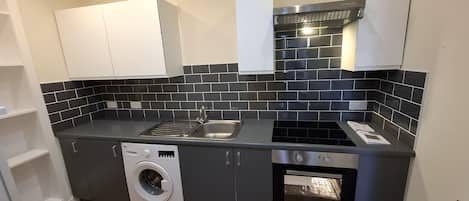 A compact kitchen with a washing machine, a built-in oven, and a sink.