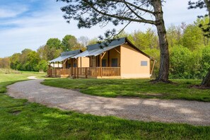 A lodge with a covered porch and a gravel path leading to it. - De Glamping - Sunny Lodge | Sleeps 6 (Zeewolde)