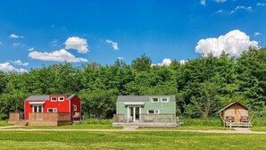 Une cabane rouge et verte avec une terrasse, entourée d’une forêt.
