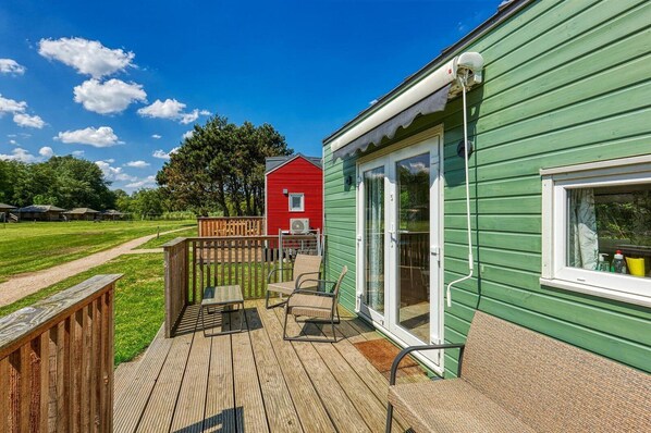 A green building with a deck, a red building in the background, and a clear sky.