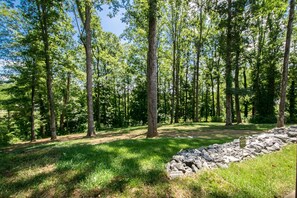 A forested area with a stone wall and a sign indicating a protected area. - Cozy Lower Retreat II Sleeps 4 Free Tix (Hendersonville)