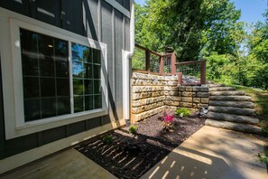 A house with a stone retaining wall, a wooden deck, and a window with a grid pattern. - Cozy Lower Retreat II Sleeps 4 Free Tix (Hendersonville)