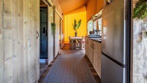 Un pasillo estrecho con paredes de madera, un tapete estampado, una zona de comedor con mesa y sillas, y un refrigerador.