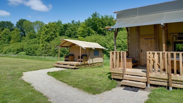 Un camping con dos cabañas de madera, cada una con un porche y zona de estar.