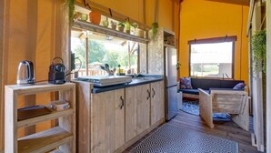 Cocina compacta con armarios de madera, un lavamanos y una cafetera. Hay una ventana que proporciona luz natural y vistas al exterior.
