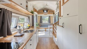 Eine kleine Küche mit Holzausziehtisch, Spüle und Essecke mit einer Bank.
