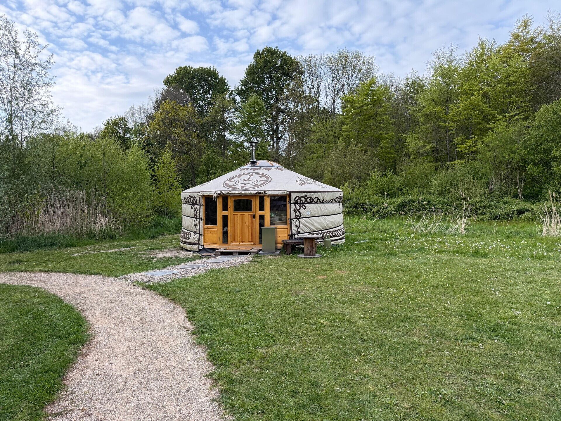 A yurt with a wooden door and a gravel path leading to it.