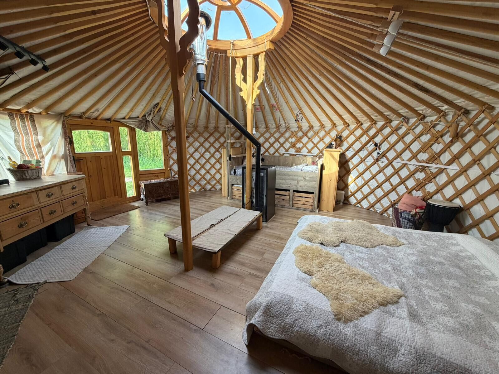 A yurt interior with a wooden bed, a desk, and a chair.