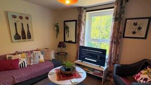 Ein Wohnzimmer mit einer Couch, einem Couchtisch und einem Fernseher.