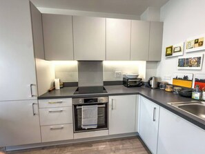 A modern kitchen with built-in appliances, a stainless steel sink, and a tiled backsplash. - #177 Stylish Finsbury Park Retreat - Sleeps 2 (Greater London)
