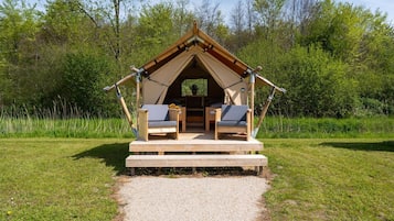 Ein Zelt mit Holzterrasse, zwei Stühlen und einem Tisch.